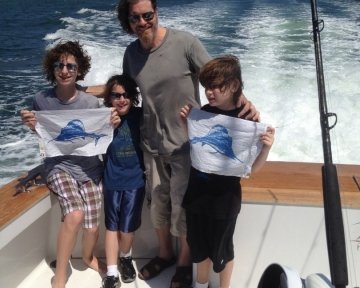 guy with three kids on a boat holding flags